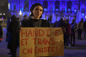 personne tenant une pancarte "handi et trans, on existe"